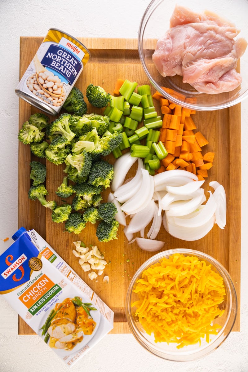 ingredients for chicken broccoli cheddar soup on a cutting board spaced out. 