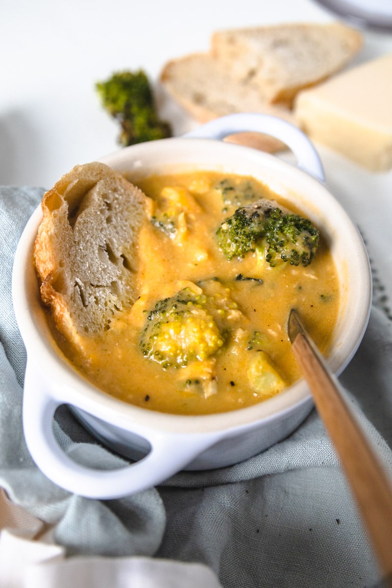 a bowl of broccoli cheddar soup with chicken with a spoon coming out of the side. 