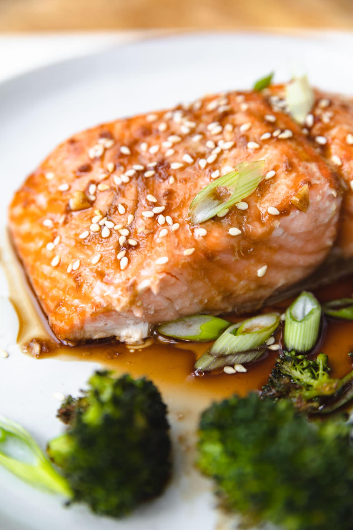 a side view of a filet of salmon cooked with scallions and sesame seeds on top. 