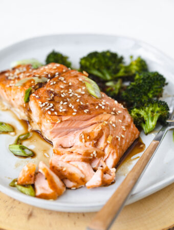 flaked apart salmon on a plate with broccoli.