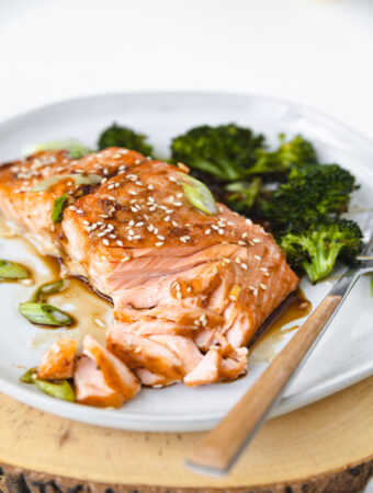 ORANGE GINGER SALMON FILET WITH A FORK AND BROCCOLI ON A PLATE.
