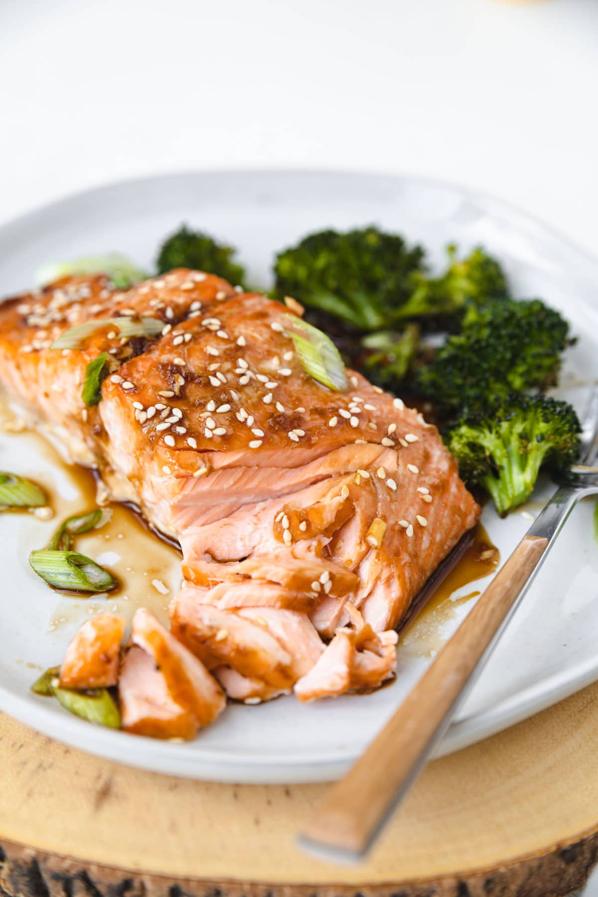 salmon topped with sesame seeds and flaked with a fork.On a plate with broccoli.