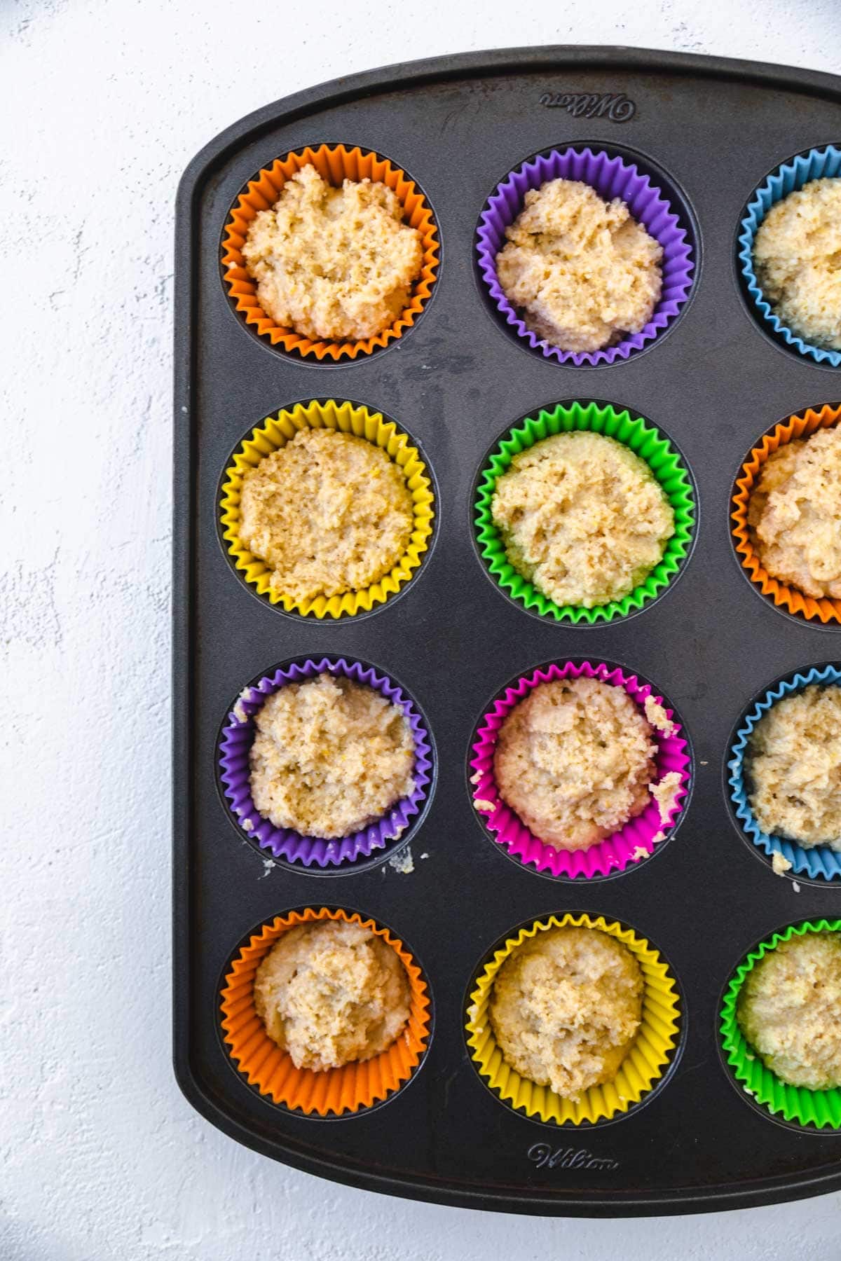 Muffin batter in muffin tins filled halfway full.