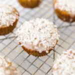 Lemon coconut muffin on a cooling rack with shredded coconut on top.