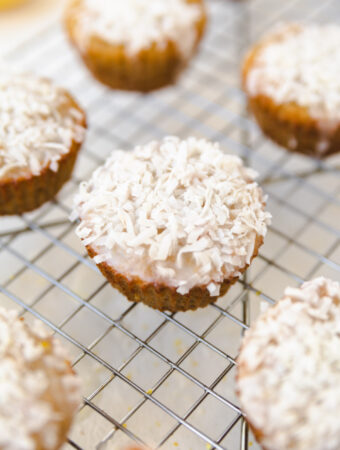 Lemon coconut muffin on a cooling rack with shredded coconut on top.