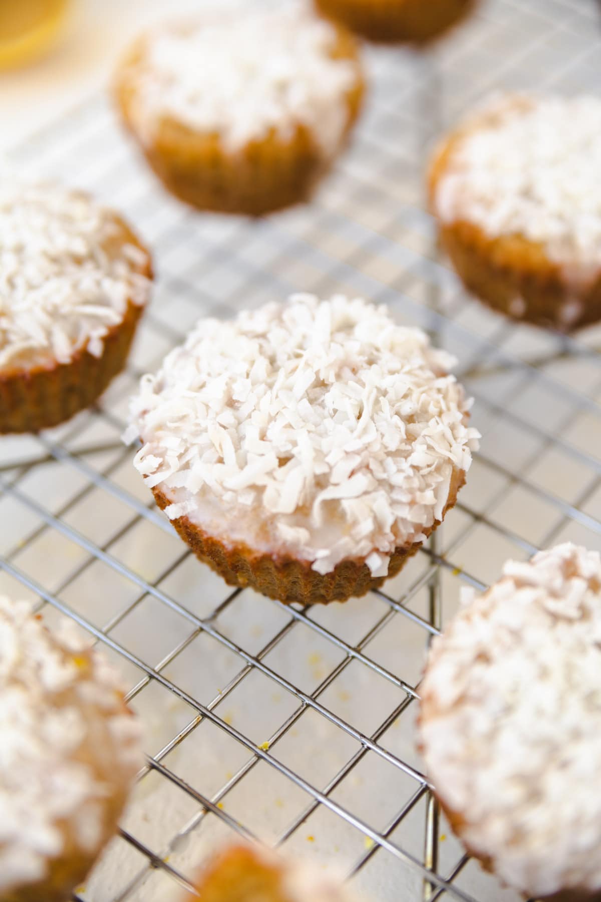 Lemon coconut muffin on a cooling rack with shredded coconut on top.