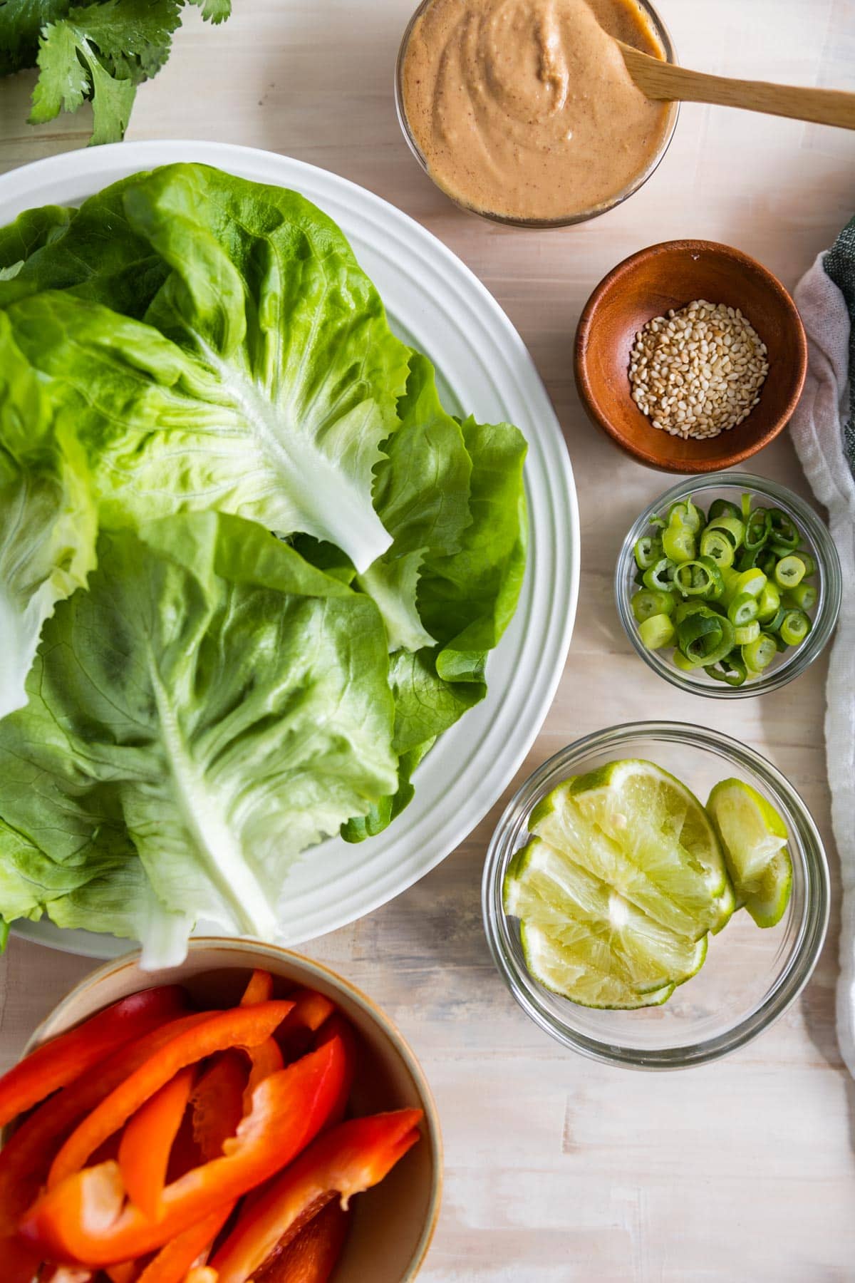 ingredients for lettuce wraps with peanut sauce displayed in bowls. Lettuce in on a plate. 