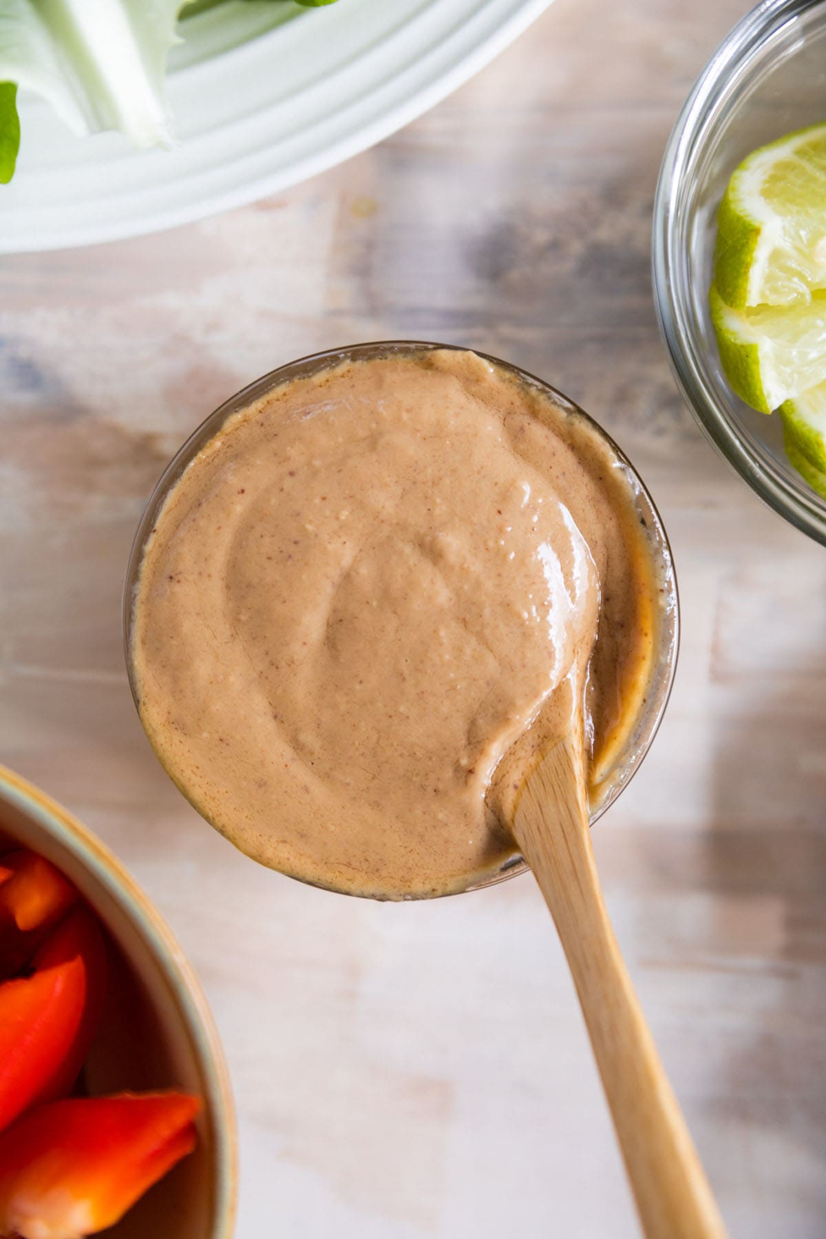 peanut sauce in a small bowl with a wooden spoon sticking out of it.
