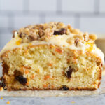 carrot cake bread sliced in half with frosting and walnuts on top.