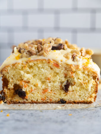 carrot cake bread sliced in half with frosting and walnuts on top.