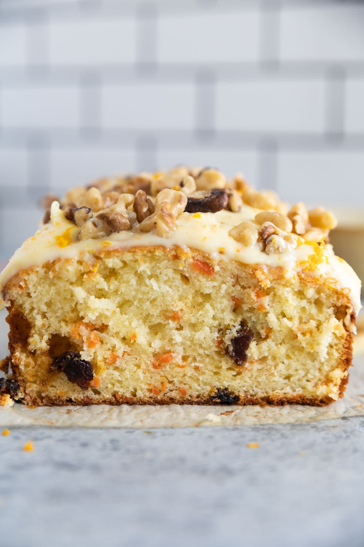 carrot cake bread with walnuts on top and orange zest. The bread is cut so the insides are showing
